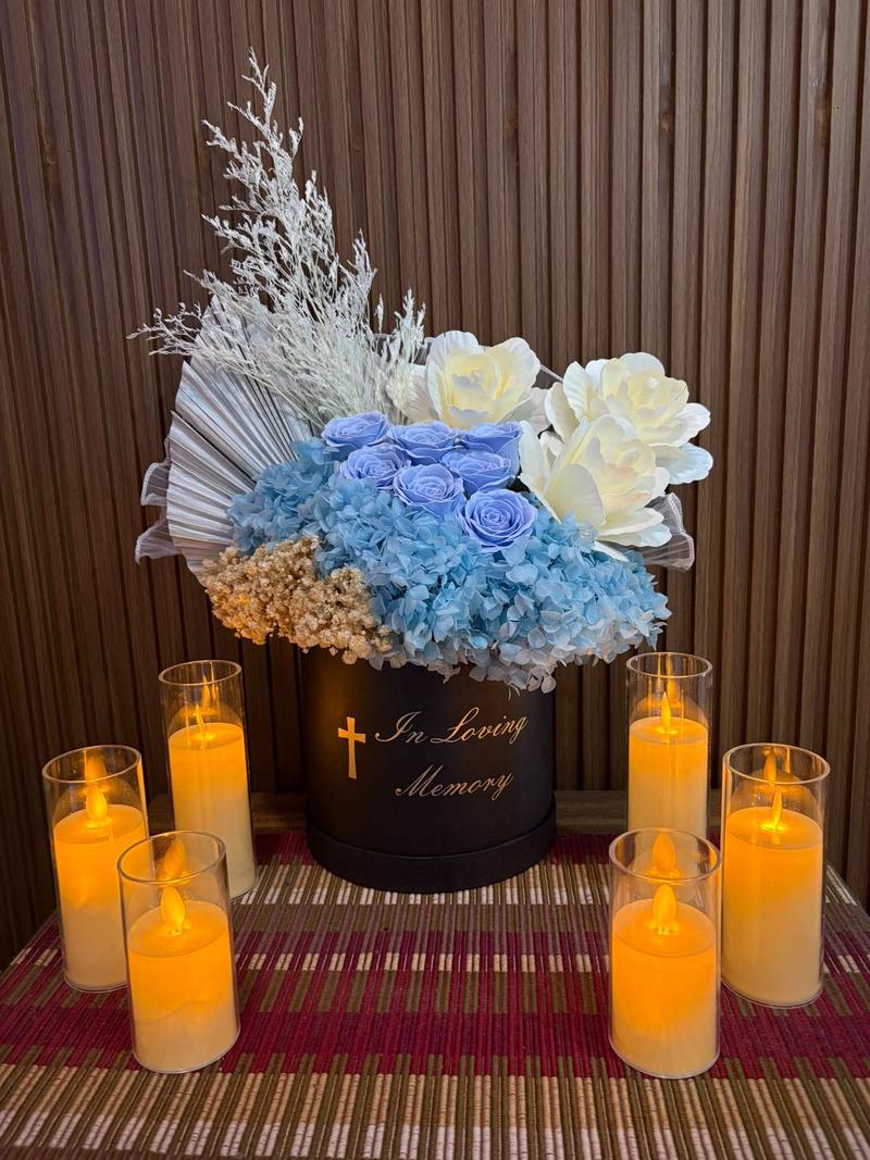 Blue roses and blue hydrangea in a black box marked In Loving Memory