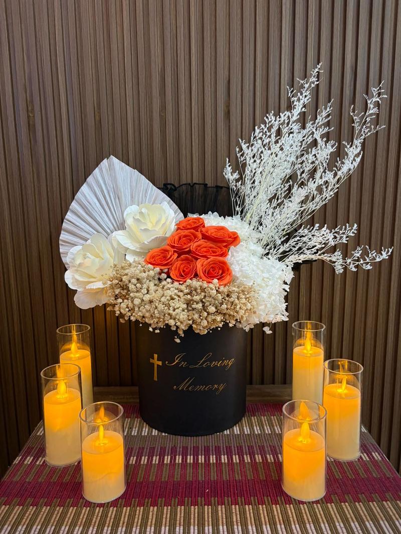 Orange roses and white hydrangea in a black box marked In Loving Memory