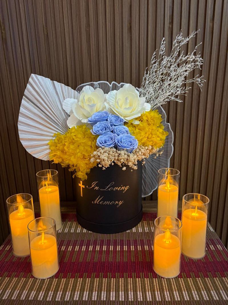Blue roses and yellow hydrangea in a black box marked In Loving Memory