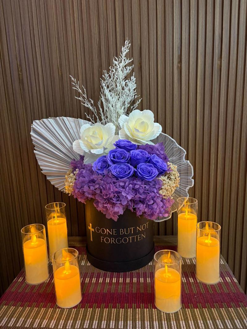 Purple roses and purple hydrangea in a black box marked Gone But Not Forgotten