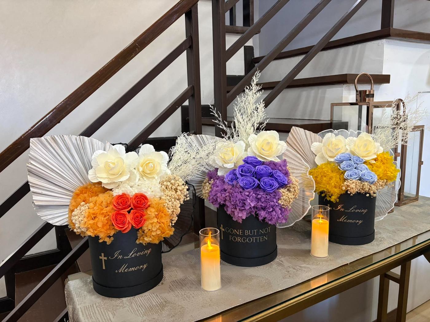 Three bouquets on a console table beside a flameless candle